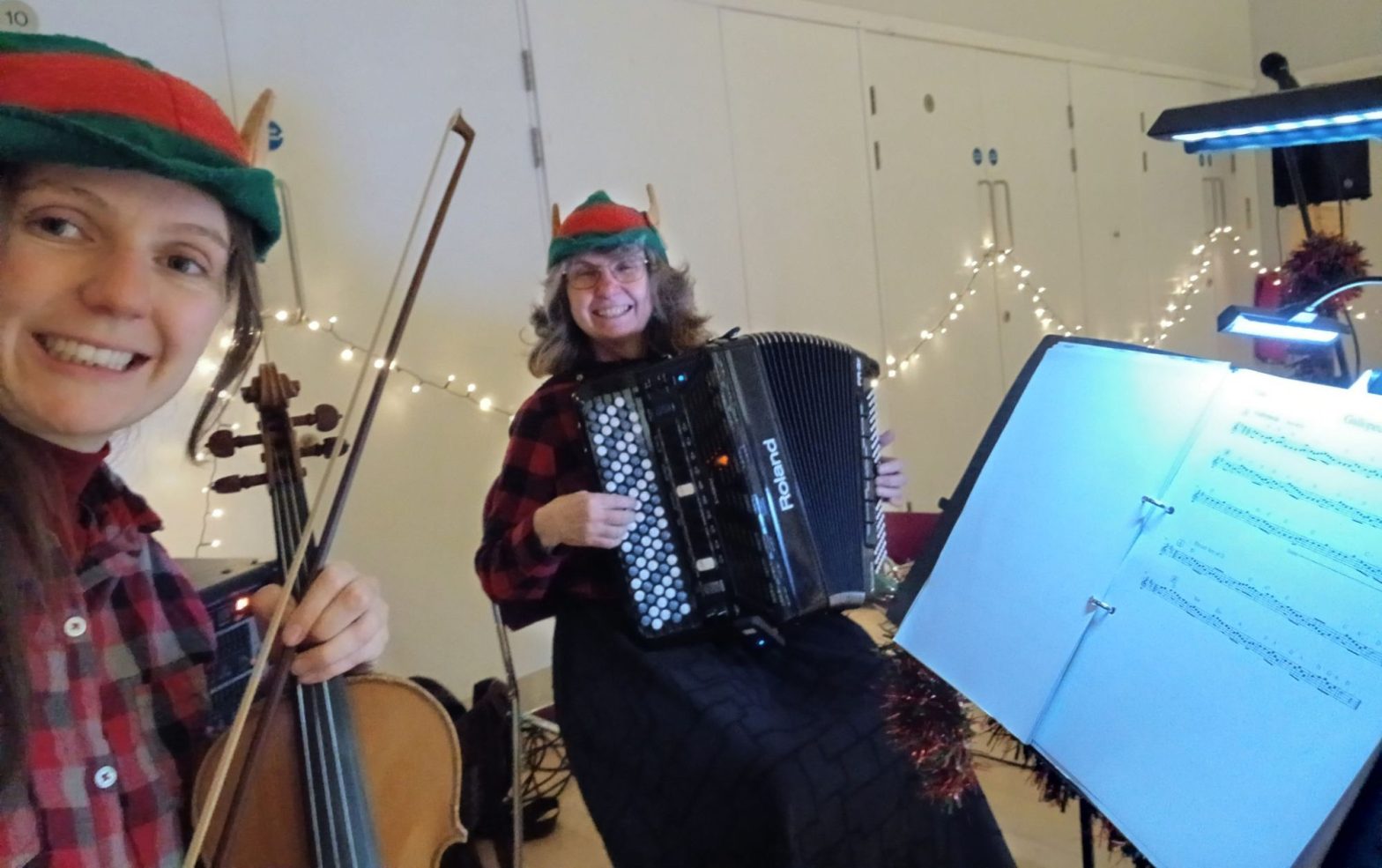 Laura with her fiddle and Judy with her accordion. Both wearing Christmas elf hat!