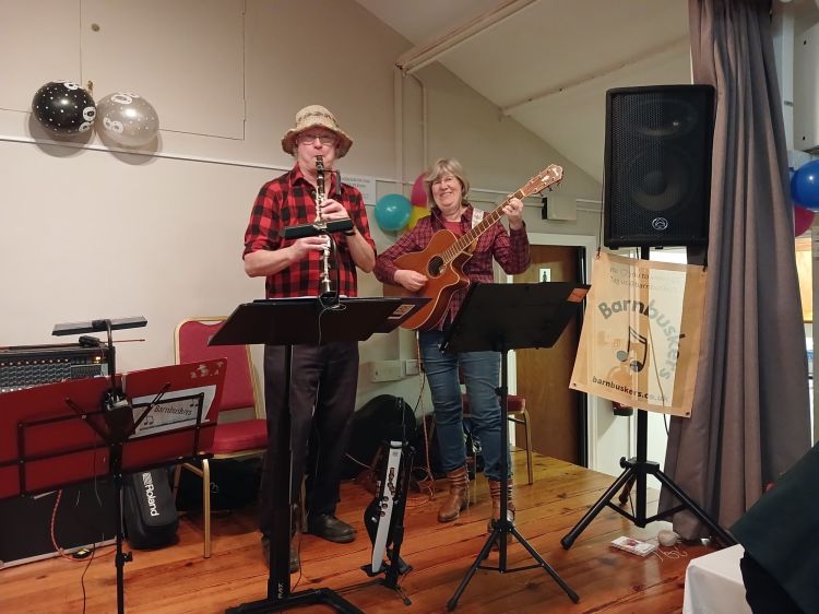 Leigh on Mendip Memorial Hall stage with Barnbuskers Ceilidh Band musicians